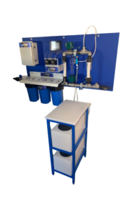 Industrial water filtration system with multiple blue filters and white storage tanks on a metal frame. Various control components are mounted on a blue vertical panel.