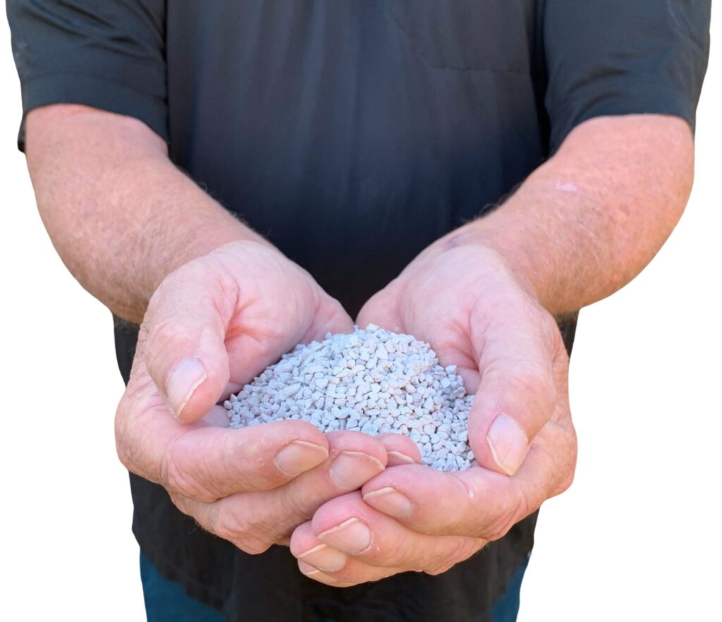 A person in a black shirt holds a mound of small gray pebbles in their cupped hands.